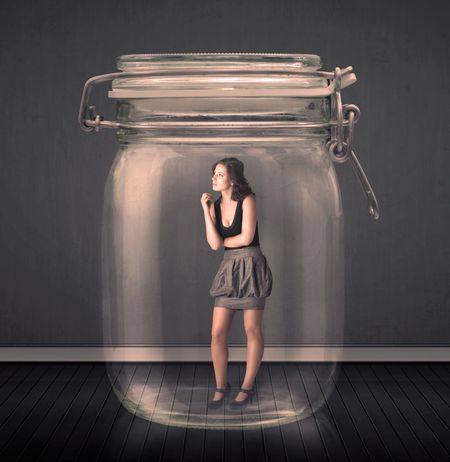 Businesswoman trapped into a glass jar concept on background