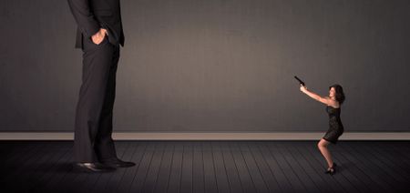 Little bussineswoman in front of a giant boss legs concept on background