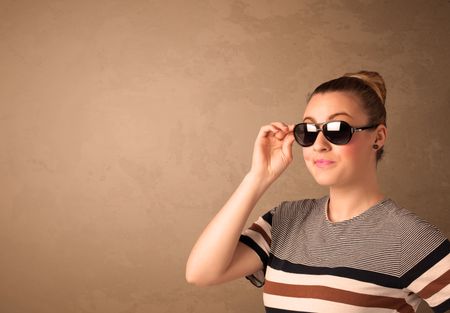 Portrait of a young pretty woman with sunglasses and copyspace on brown background
