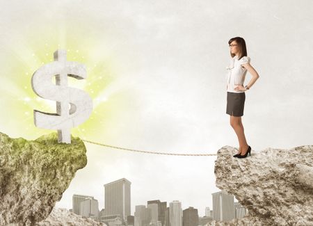 Businesswoman standing on the edge of mountain with a shining dollar mark on the other side