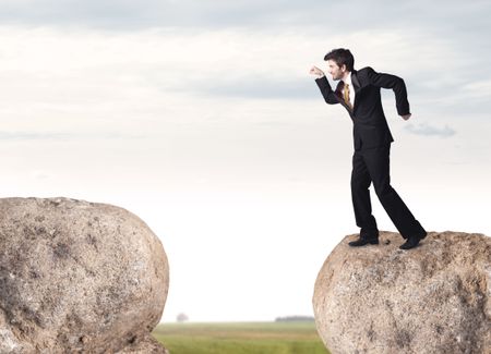 Young businessman standing on edge of rock mountain