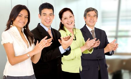 business office team smiling and applauding while facing the camera