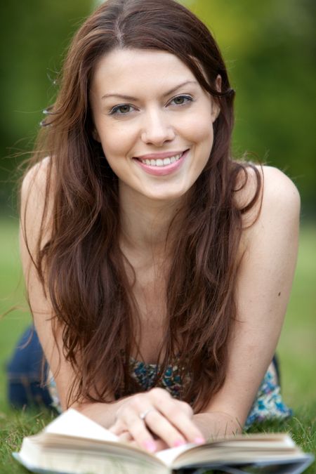 beautiful-woman-outdoors-reading-book-smiling-35212234 BEautiful woman outdoors reading a book and smiling