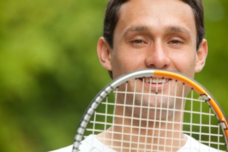 Man outdoors holding a tennis racket in front of his face
