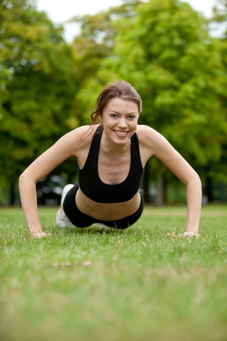 Thin athletic woman doing push-ups at a park