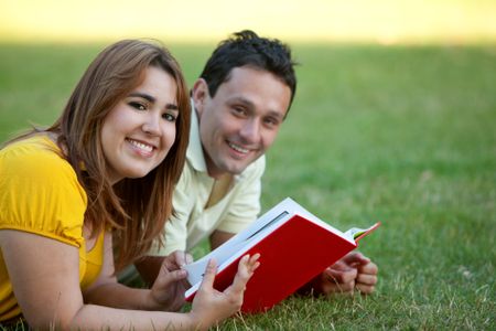 Beautiful couple studying outdoors with a notebook