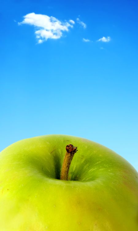 green apple close up with a beautiful blue sky in the background