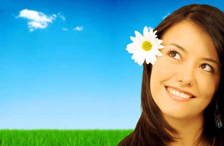 beautiful spring or summer girl smiling outdoors - she has a white daisy flower on her head and she has a thoughtful and expressive face