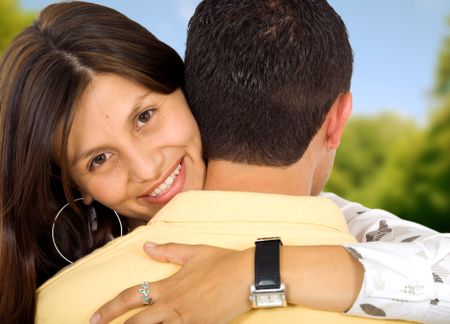 girl smiling while hugging her boyfriend outdoors in a park