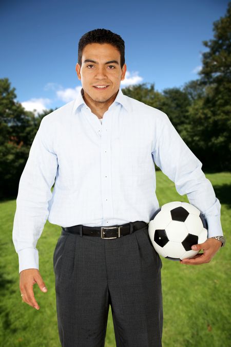 Formal man with a football at a park