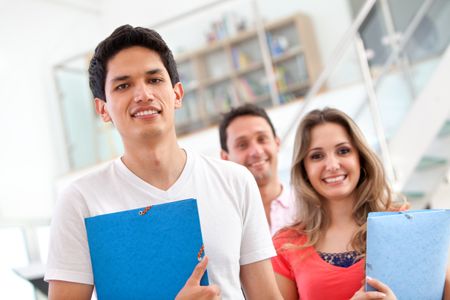Casual group of students with folders smiling  indoors
