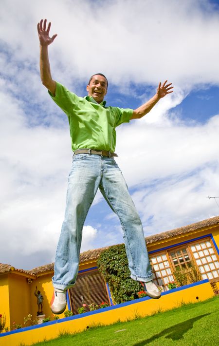 casual man jumping in the air outside his house