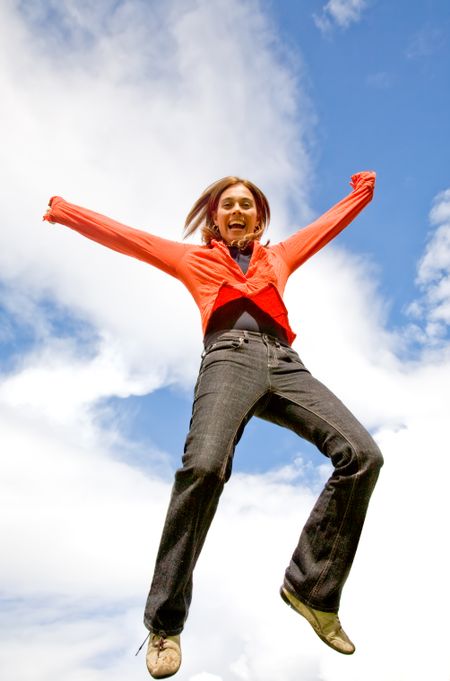 casual girl looking very happy in mid air - jumping over a blue sky