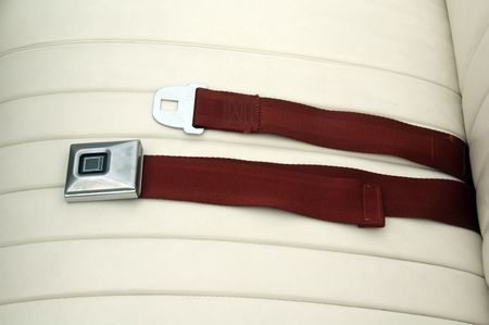 Seat belt, unbuckled, on leather seat of classic car