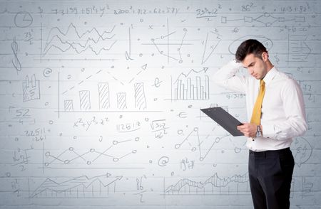 A confident young businessman standing in front of wall with drawn pie charts, graphs, numbers, arrows concept
