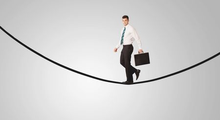 A confident smiling salesman balancing on black wire in clear grey empty space concept