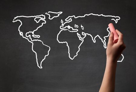 A teacher drawing the map of the world on a blackboard with a chalk