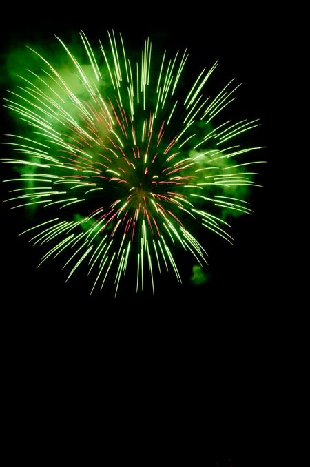 Burst of fireworks like a dandelion with green smoke