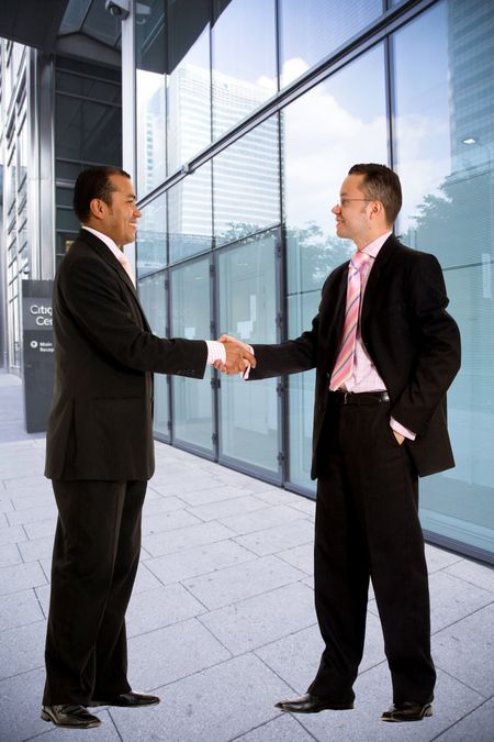 Business men handshaking outside a corporate building