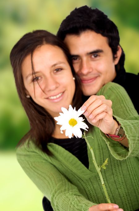 couple in love with a daisy flower - outdoors in a park over a green background
