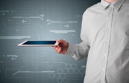 Young businessman holding a white modern tablet with blurry apps
