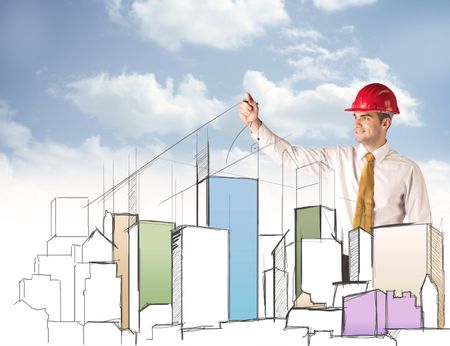 A young construction worker in a red safety helmet happily planning a city sight and drawing lines, arrows, angles, buildings with a pen in his hand