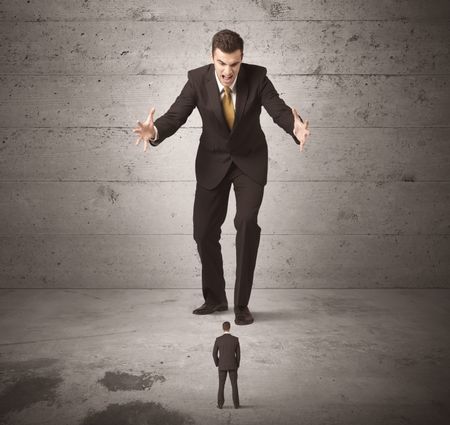 Huge angry business guy looking at small coworker concept on background