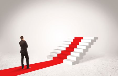 A successful businessman with briefcase standing on red carpet in front of steps in white space concept