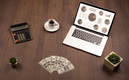 Pie chart graph icons and symbols on laptop screen with office accessories