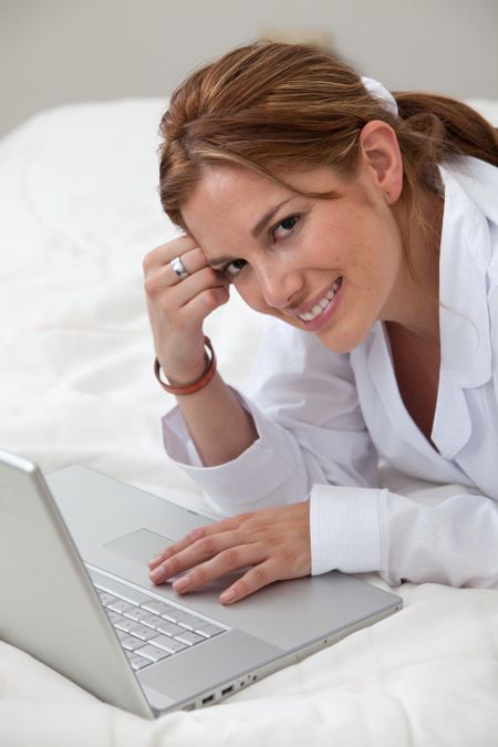 Woman in bed working on a laptop computer