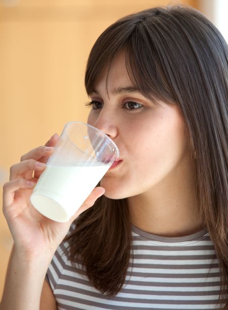 Portrait of a beautiful brunette girl drinking milk