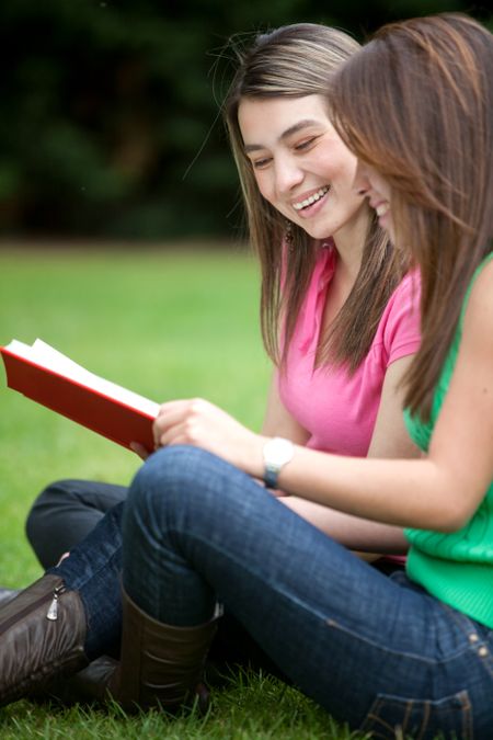 Girls studying with a notebook outdoors and smiling