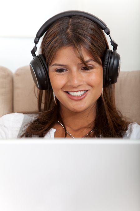 Beautiful smiley woman with headphones on the computer