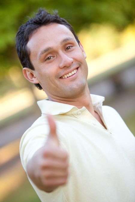 Casual man smiling with thumbs up outdoors