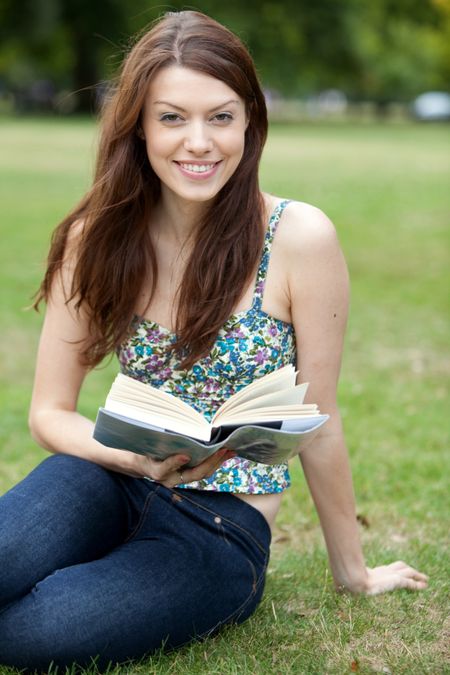 Beautiful woman reading a book at the park