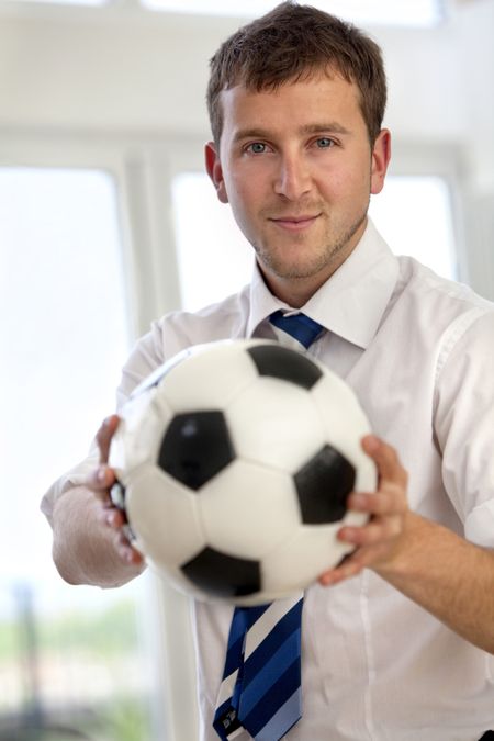 Handsome business man indoors holding a football
