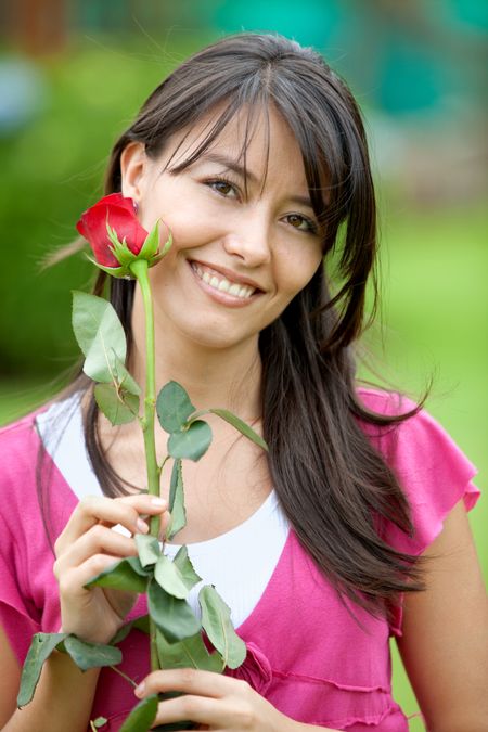 Beautiful woman with a red rose outdoors