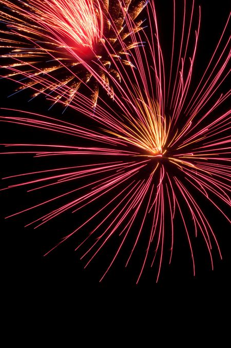 Large burst of pink fireworks by smaller burst with reddish smoke
