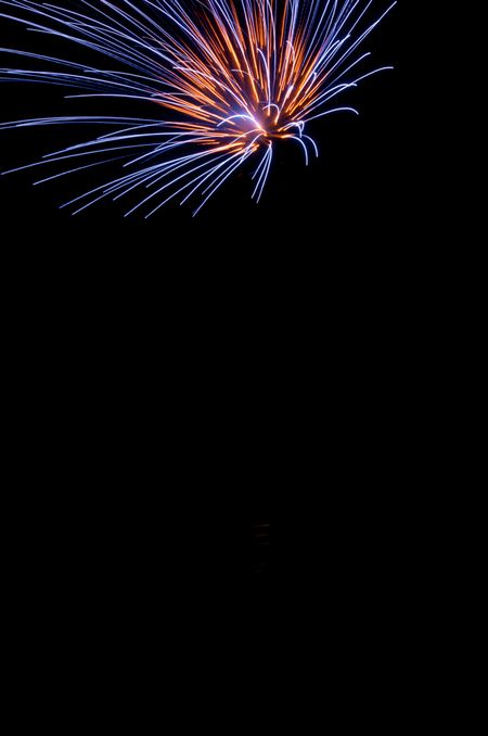 Burst of fireworks with blue and orange streaks near top of frame