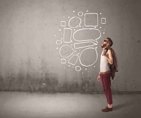 A comic hipster guy shouting in front of grey urban concrete wall with drawn empty text bubbles around his mouth concept