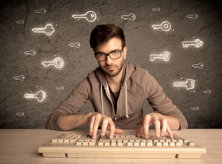A young internet geek working online, hacking login passwords of social media users concept with glowing drawn keys on the wall