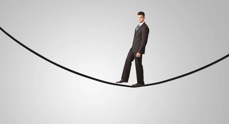 A confident smiling salesman balancing on black wire in clear grey empty space concept