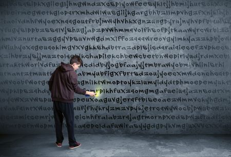 Young urban painter drawing random letters on the wall