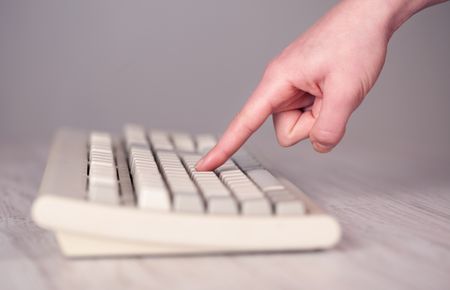 Close up of hand pressing keyboard buttons on desk