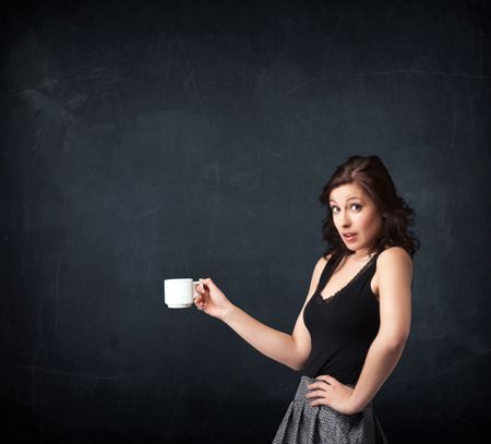 Businesswoman standing and holding a white cup on a black background
