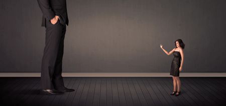 Little bussineswoman in front of a giant boss legs concept on background