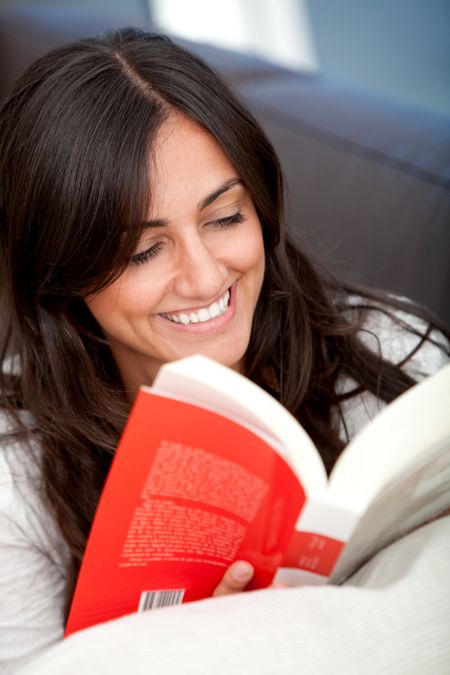 Beautiful happy woman reading a book indoors