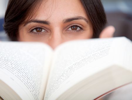 Beautiful woman holding a book in front of her face