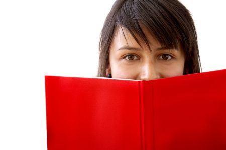Young woman covering her face with a book isolated