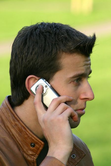 casual guy talking on a mobile phone in a park 2